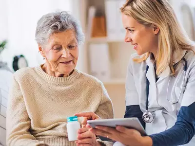 Eine Pflegekraft hilft einer Patientin mit einem Tablet