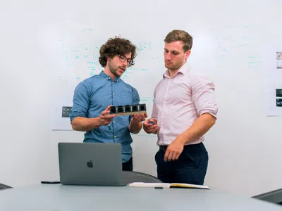 Zwei Spezialist:in Industrie 4.0 stehen nebeneinander vor einem Laptop.