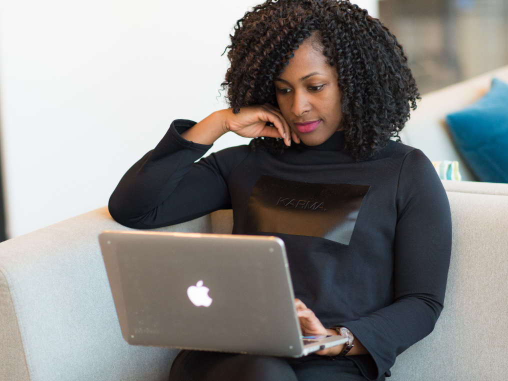 Eine Frau sitz auf einem Sessel und studiert nachhaltiges Management über ihren Laptop