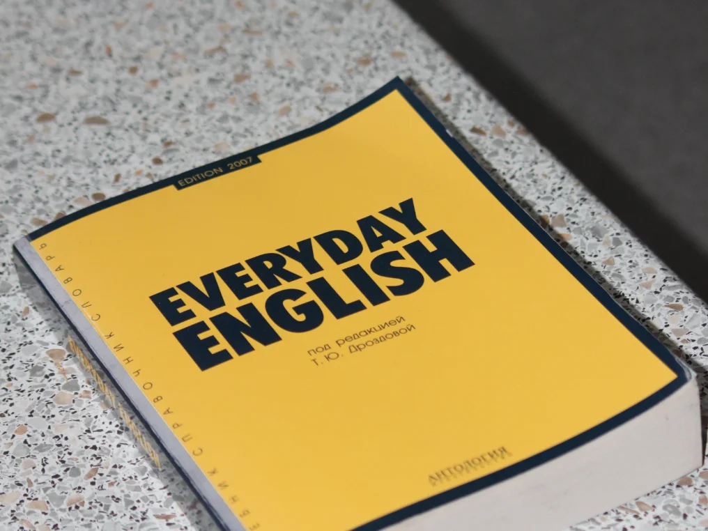 Ein Englisch Buch mit gelben Cover liegt auf einem grauen Tisch