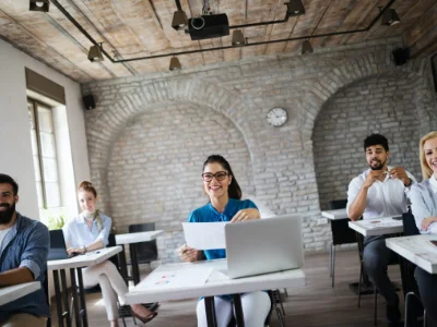 5 Studierende sitzen zusammen vor ihren Laptops in einem Klassenzimmer