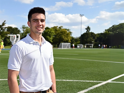 Ein Sportmanagement-Student steht auf einem Sportplatz.