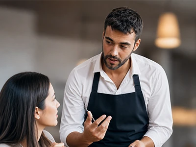 Servicekraft berät einen Gast im Restaurant.