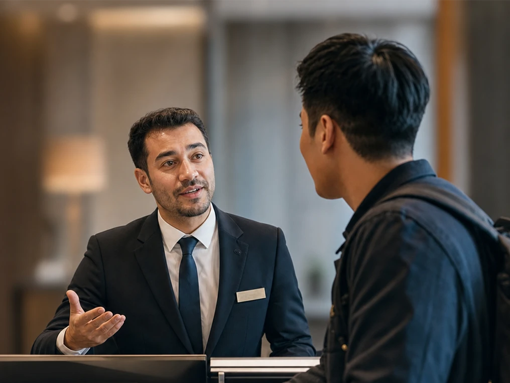 Rezeptionist berät einen Gast an der Hotelrezeption.