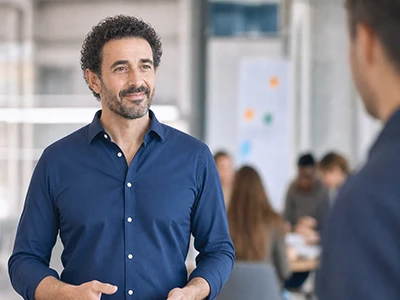 Trainer im Gespräch mit einem Kollegen während eines Workshops.
