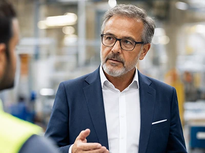 Senior Manager im Gespräch mit einem Mitarbeiter in der Produktion.