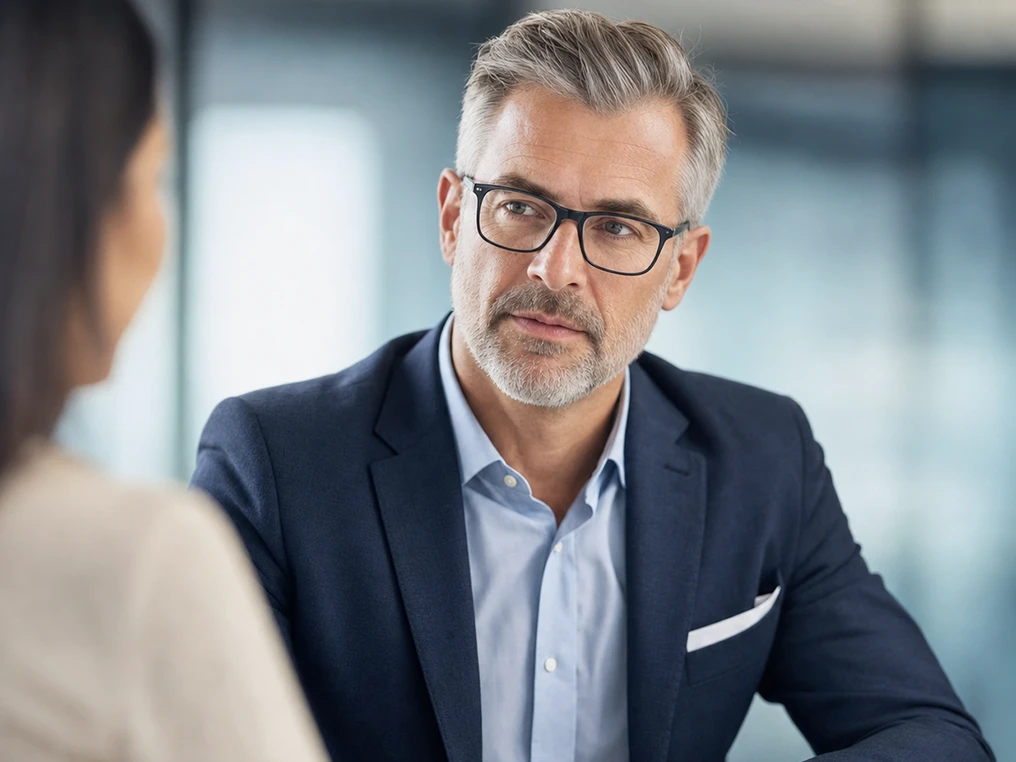 Manager im Gespräch mit einer Kollegin am Besprechungstisch.