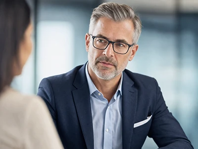 Manager im Gespräch mit einer Kollegin am Besprechungstisch.